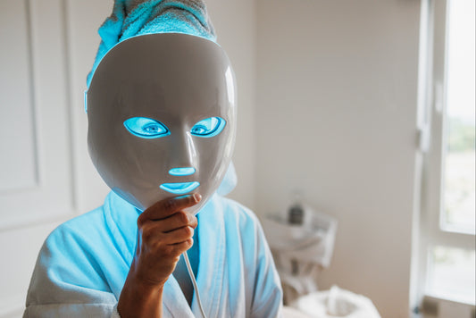 Person wearing a LED face mask in a bedroom setting